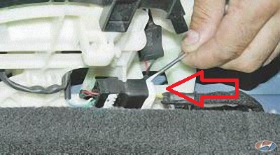 Отожмите отверткой фиксатор колодки жгута на автомобиле Hyundai Solaris